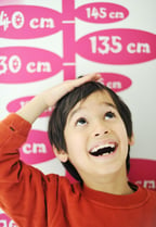 Boy growing tall and measuring his height on the wall